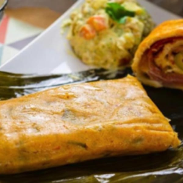Venezuelan Chamo Cuisine's hallaca, potato salad, and pan de jamón on a white plate.