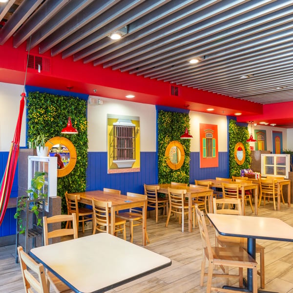 Venezuelan Chamo Cuisine dining room with blue and red walls, green plant walls, and wooden tables.